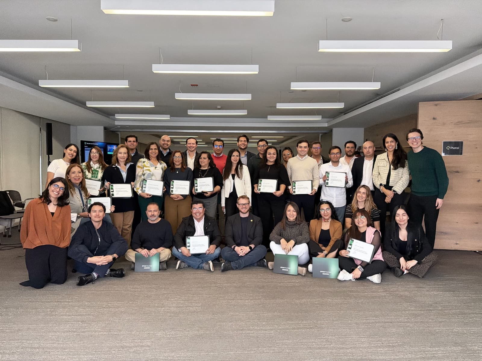 Fabián Oloarte with participants and facilitators at the conclusion of a corporate AI program, with certificates and Platzi Business materials visible.